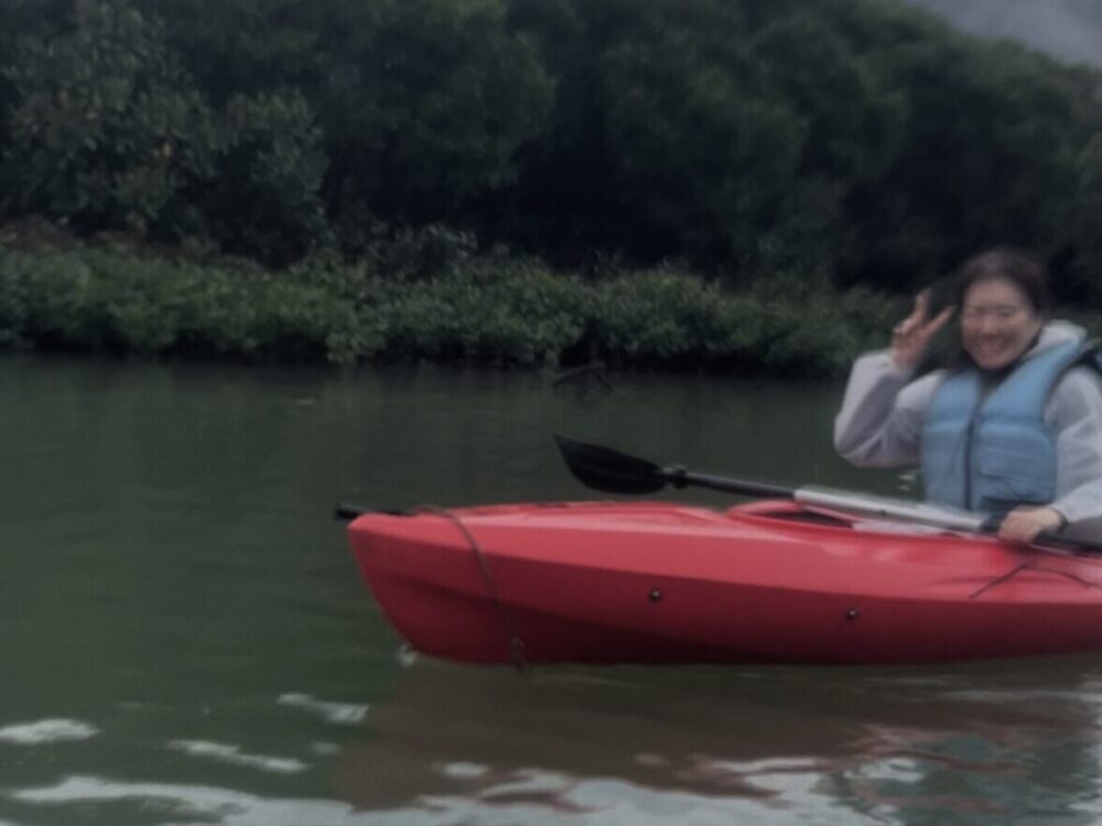 マングローブの枝がトンネルのように重なり合う狭い水路を、カヌーでゆっくりと進む神秘的な光景