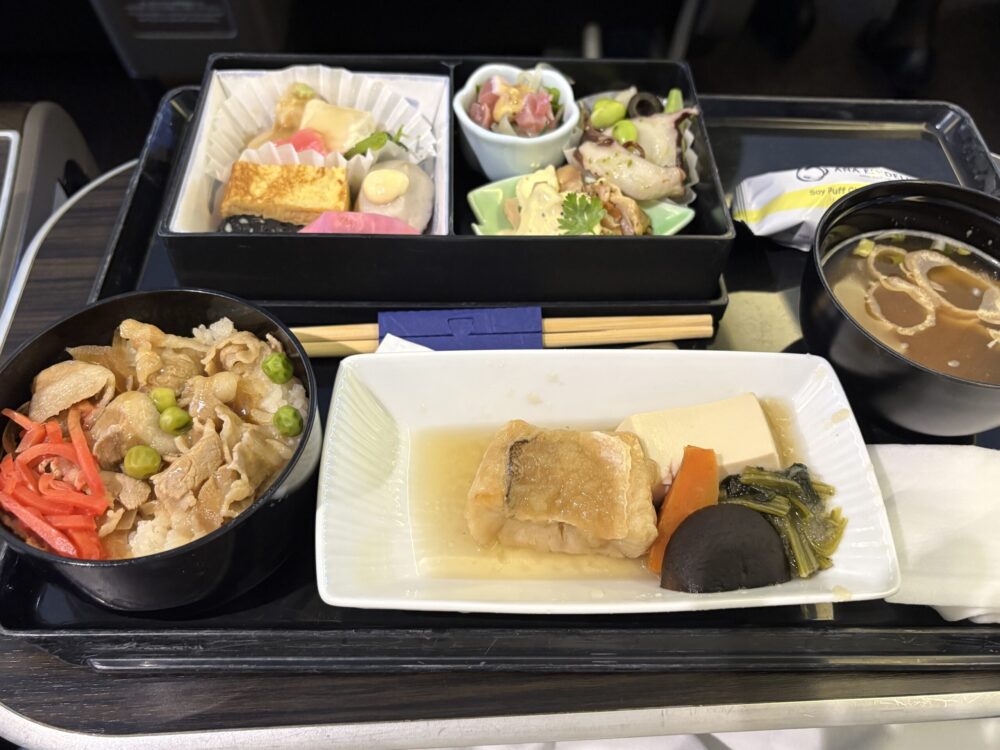 ANAプレミアムクラスで提供される季節の機内食「プレミアムGOZEN」。彩り豊かなお料理がお重に詰められ、温かいお味噌汁が添えられた豪華なトレイ