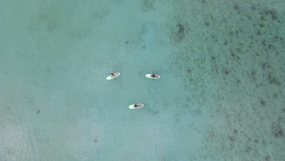 ドローンで上空から撮影した、透明な海に浮かぶSUPボードと美しい海