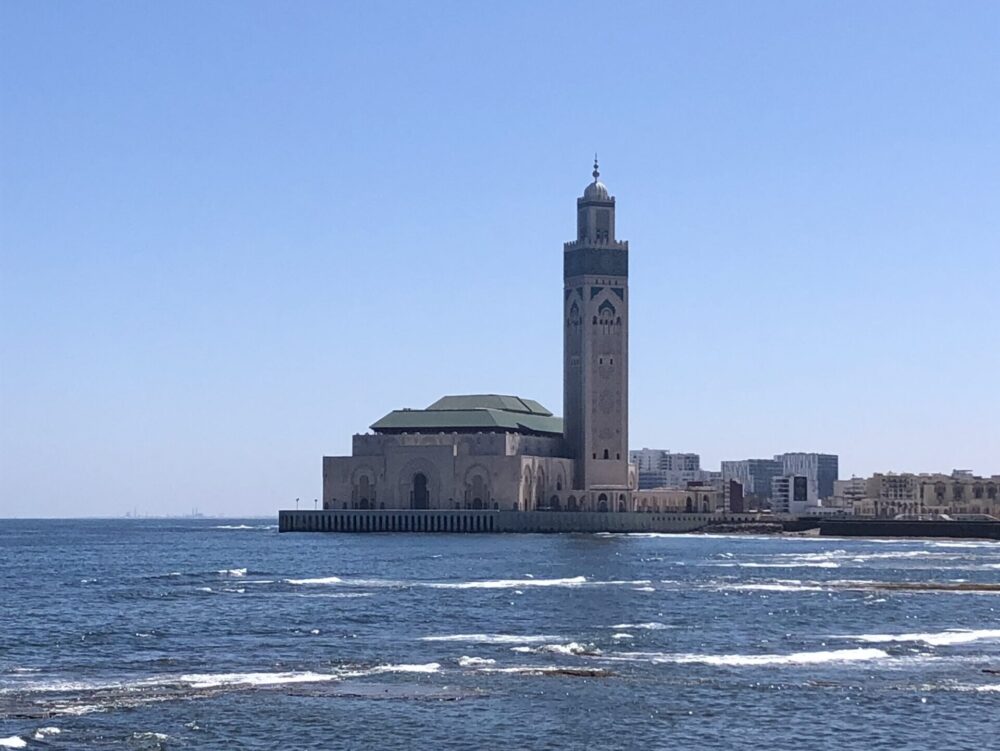 大西洋の海に面して建つハッサン2世モスクの壮大な外観。白い大理石と緑のタイルが美しい
