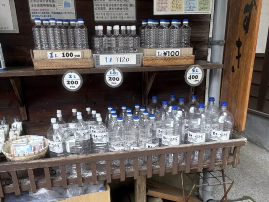 白川水源の入り口にある売店に並ぶ、水汲み専用の空のペットボトル。500mlから大きなサイズまで揃っており、誰でも名水を持ち帰ることができる