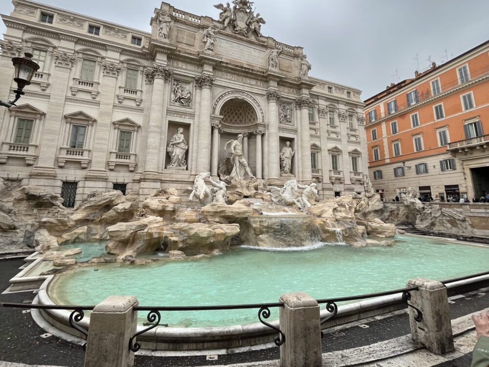 ターコイズブルーの美しい水が流れるトレビの泉と背後の彫刻