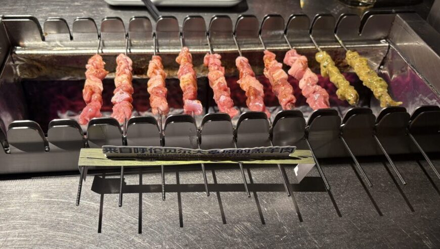 自動回転する串焼きグリルで焼かれる羊肉串